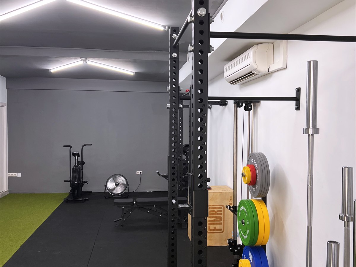 Power rack de sentadilla, barra de dominadas, barra olímpica y air bike en Nexus